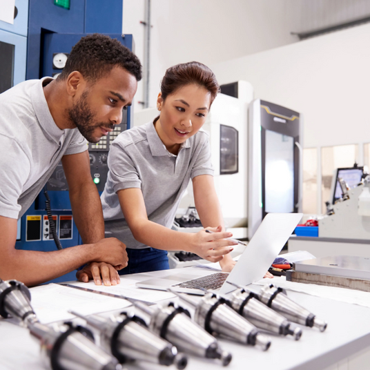 People looking at a computer with parts around them